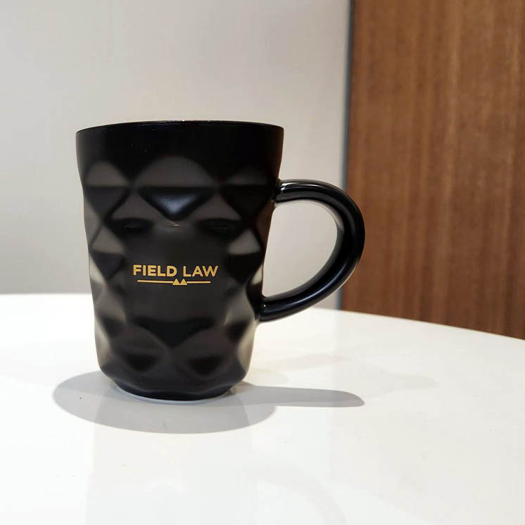 Black mug with Field Law logo in gold Black mug with Field Law logo in gold